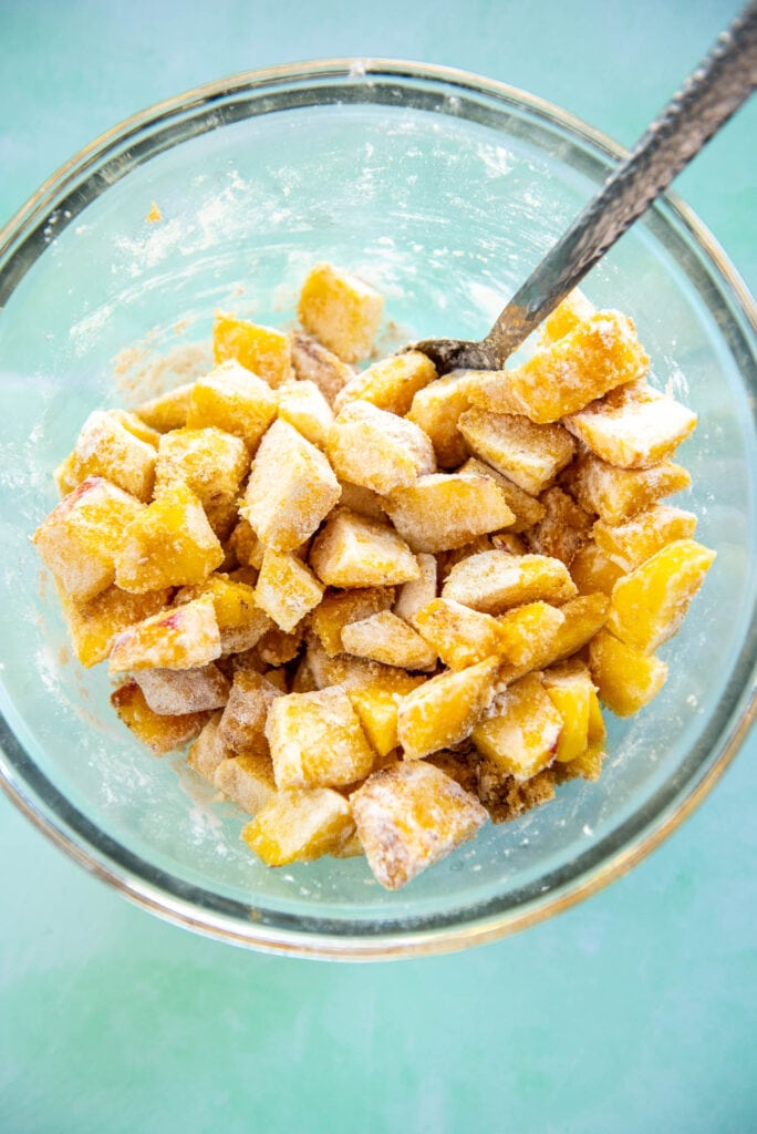 glass bowl with chopped peaches mixed with flour