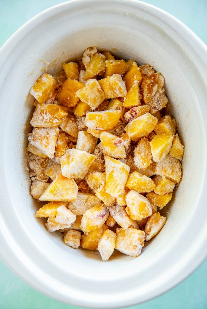 peach cobbler mixture in white slow cooker