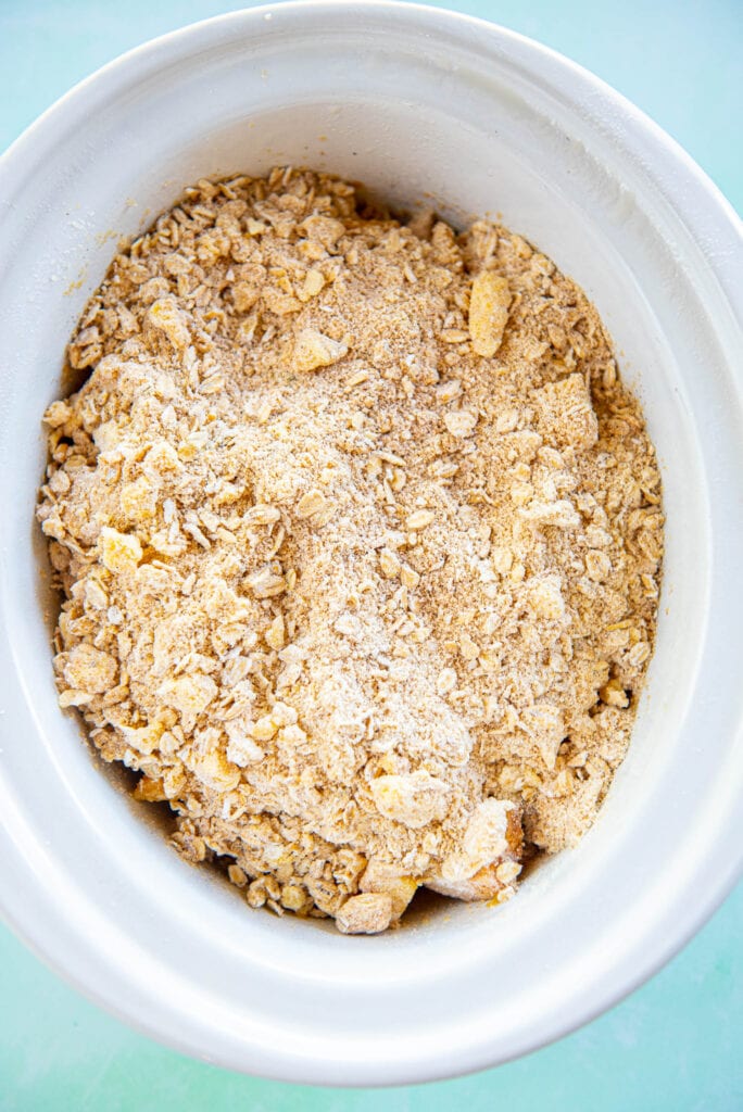 peach cobbler filling and topping in white slow cooker