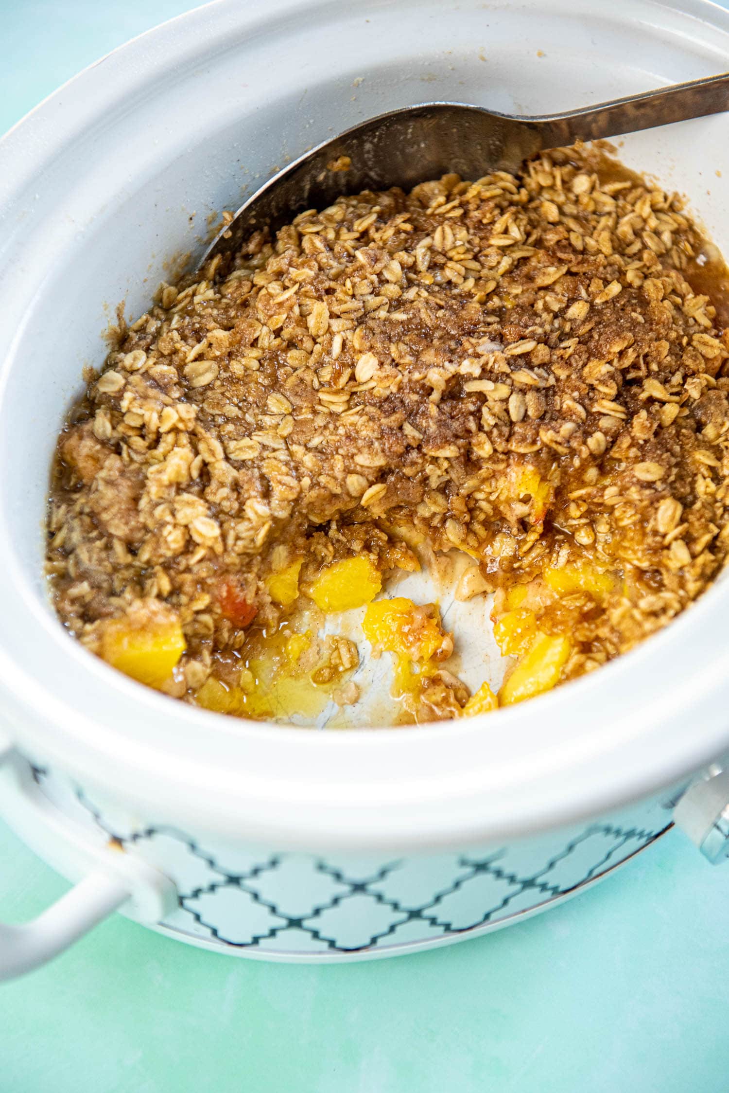 slow cooker with peach cobbler scooped out