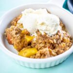 white ramekin with peach cobbler topped with ice cream