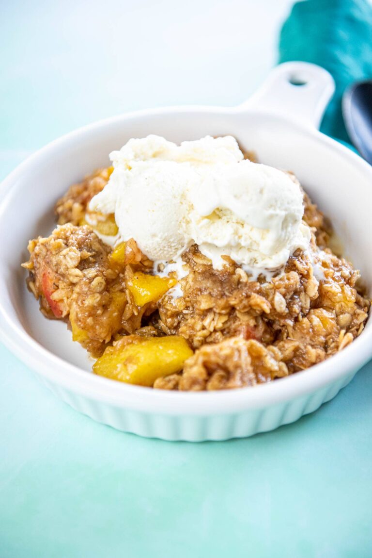 white ramekin with peach cobbler topped with ice cream