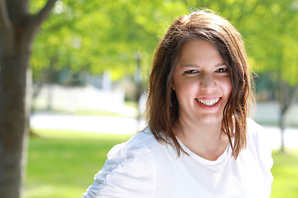 woman in white shirt with trees in background