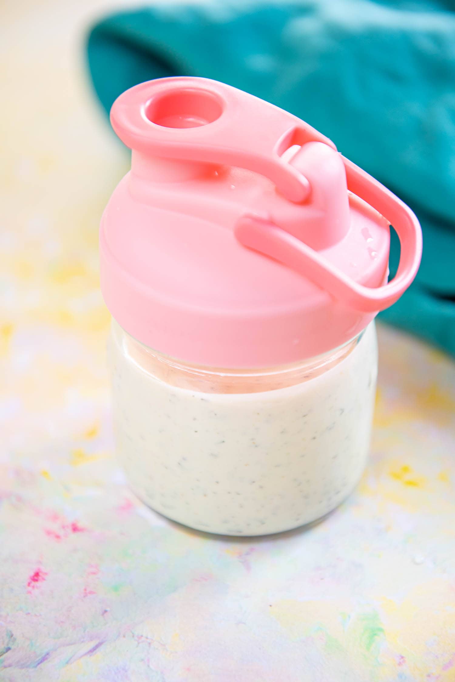 small mason jar with pink lid filled with homemade ranch dressing