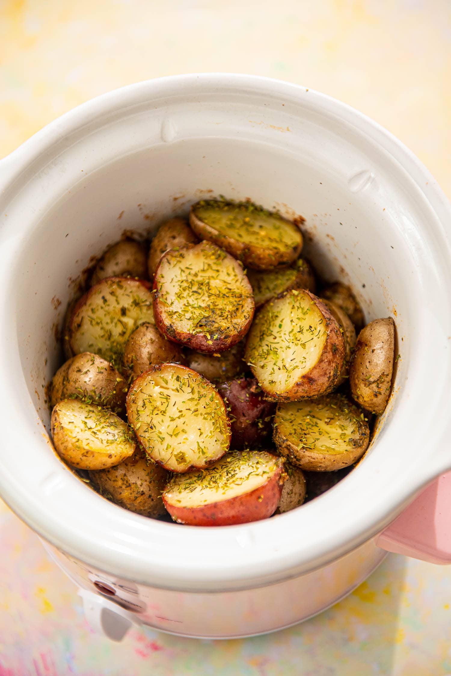 pink slow cooker with roasted baby potato halves with seasoning