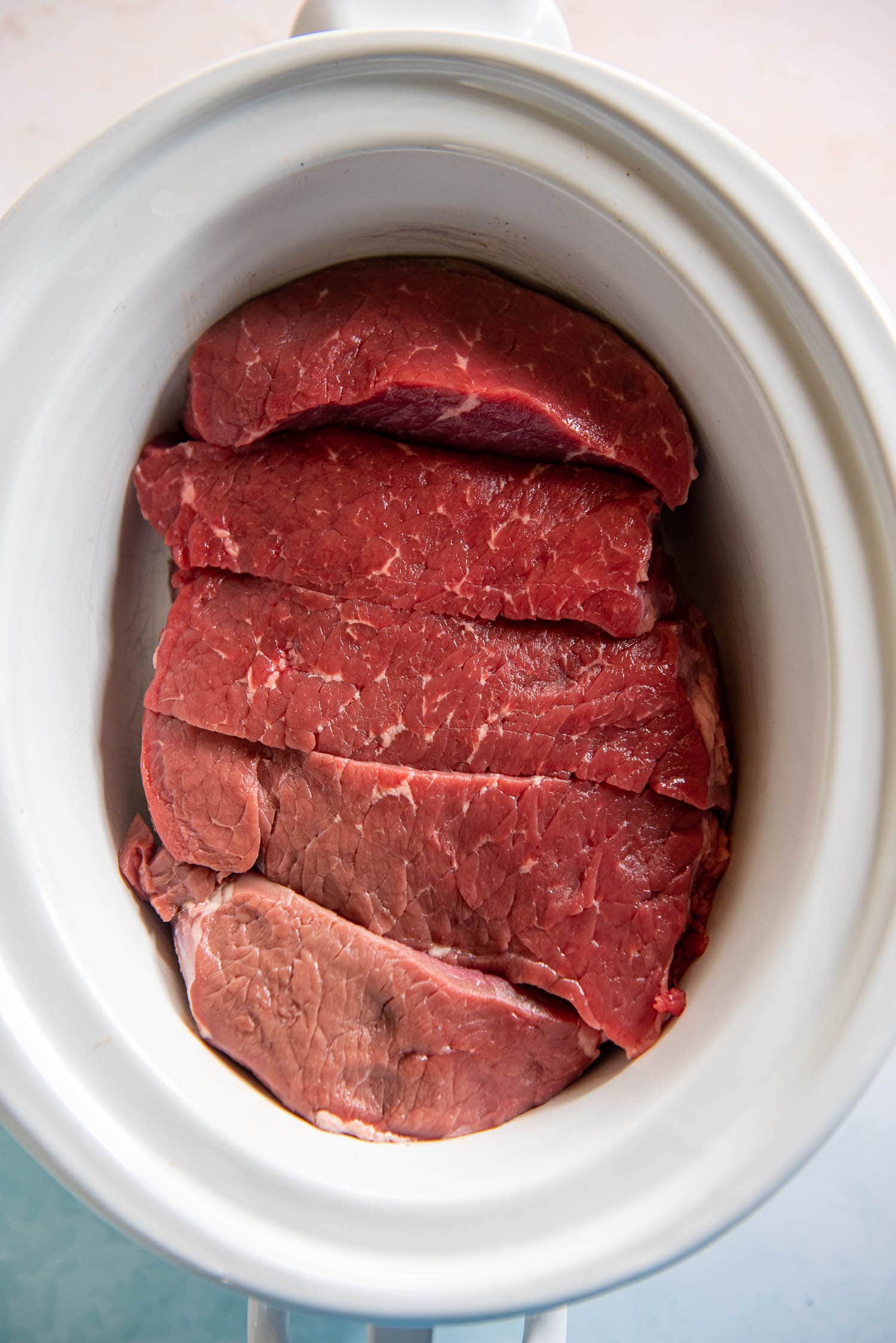 raw beef inside of a slow cooker