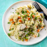 white plate with chicken and rice casserole and black fork