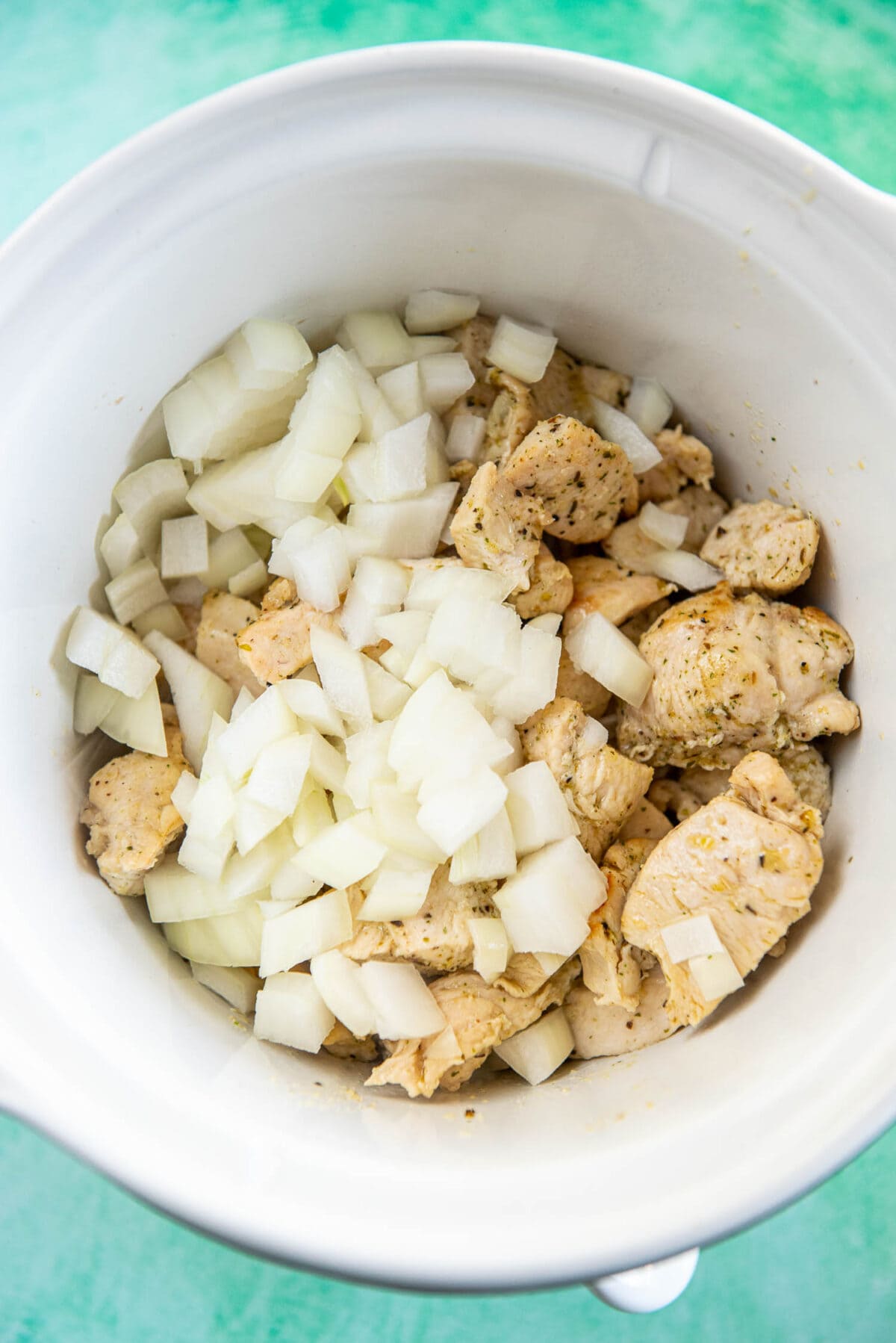 chicken pieces and chopped onions in slow cooker