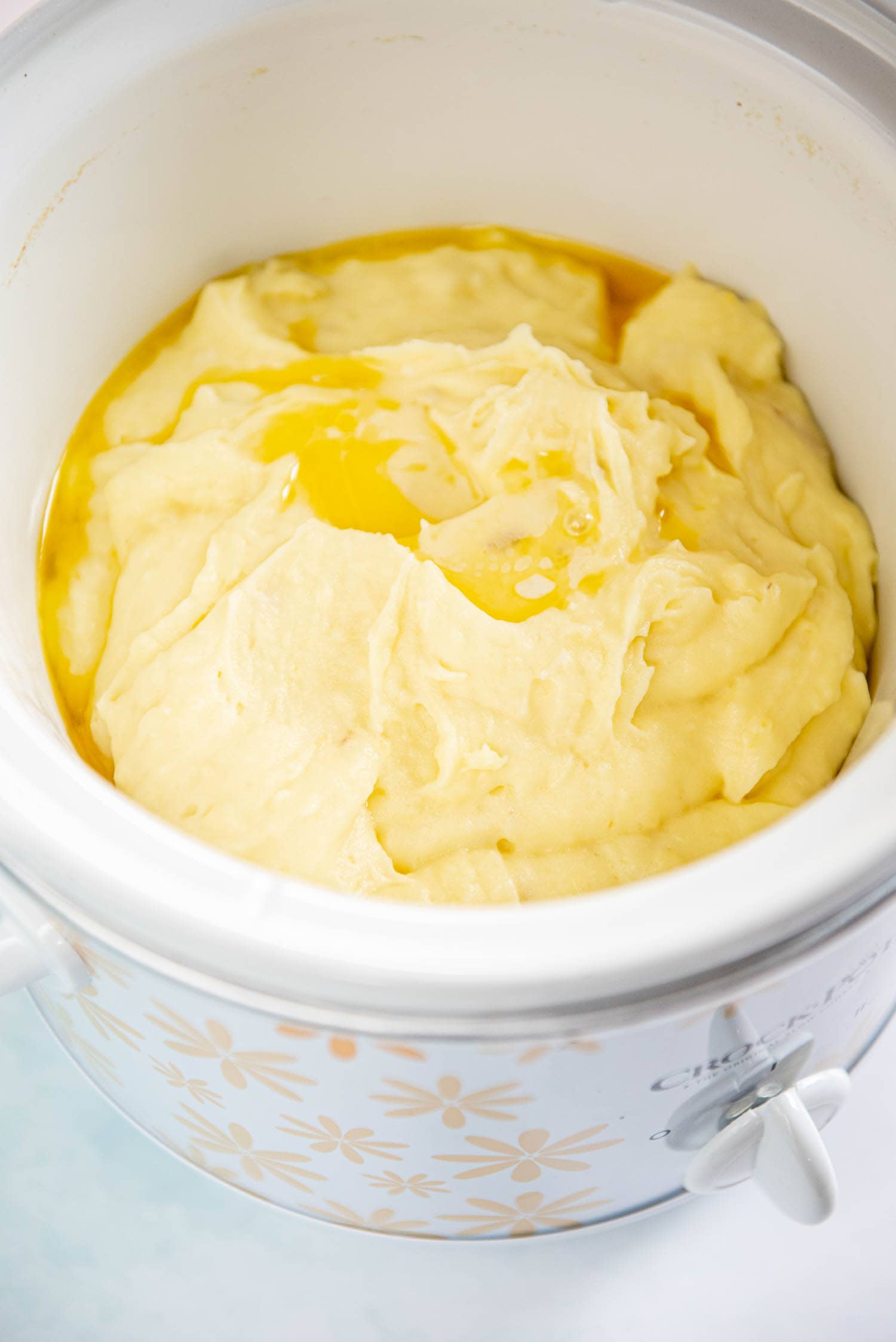 mashed potatoes with butter melting on top inside of slow cooker