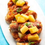 chicken tenders with bbq sauce and pineapple chunks stacked on platter