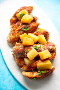 chicken tenders with bbq sauce and pineapple chunks stacked on platter