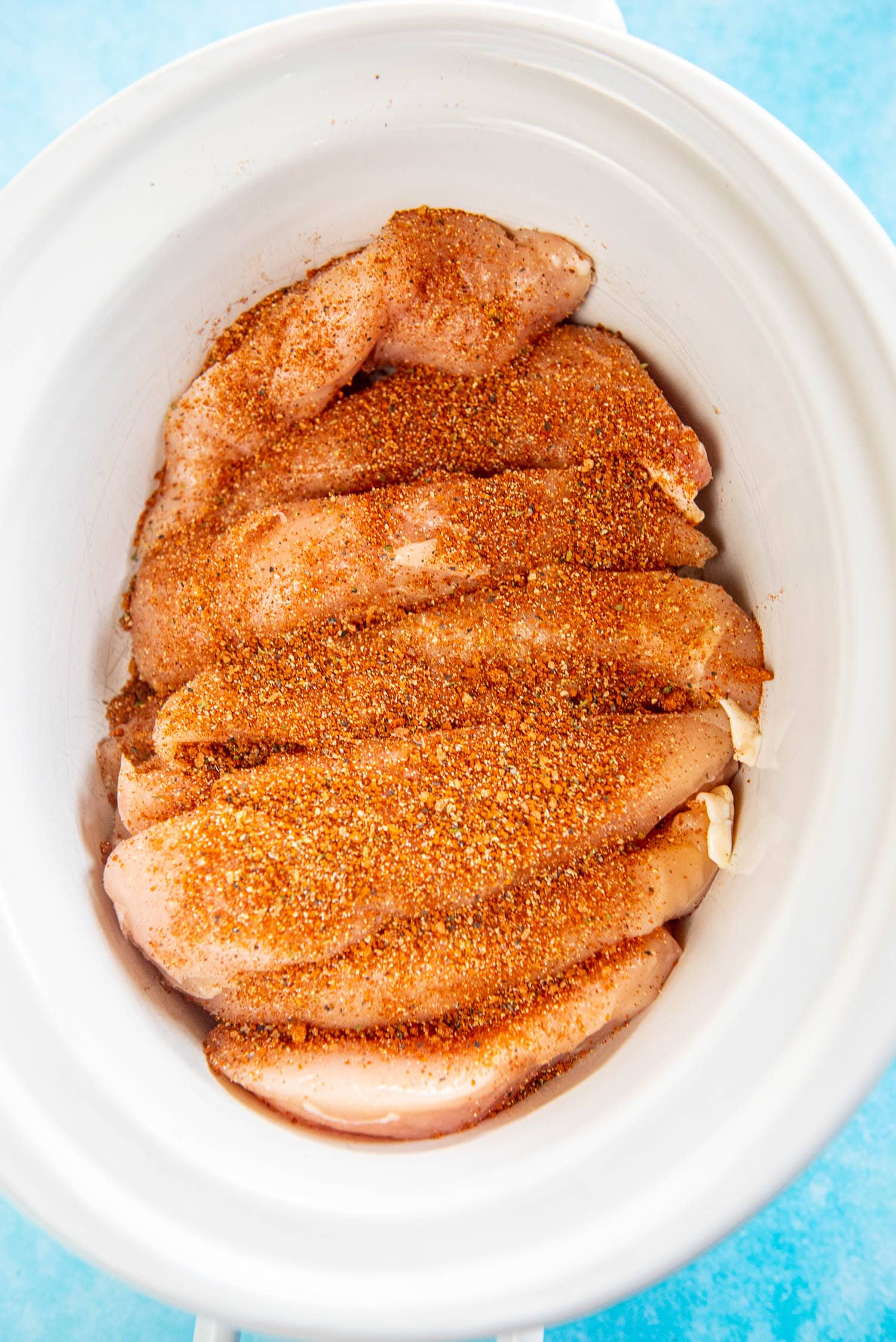 chicken tenderloins coated with seasoning in slow cooker