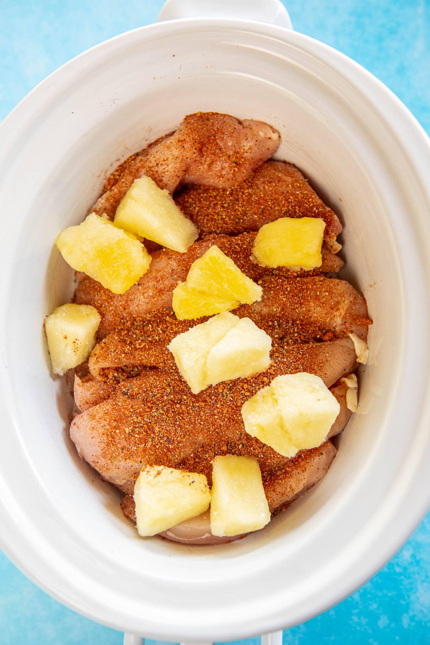 chicken with seasoning and frozen pineapple chunks in slow cooker