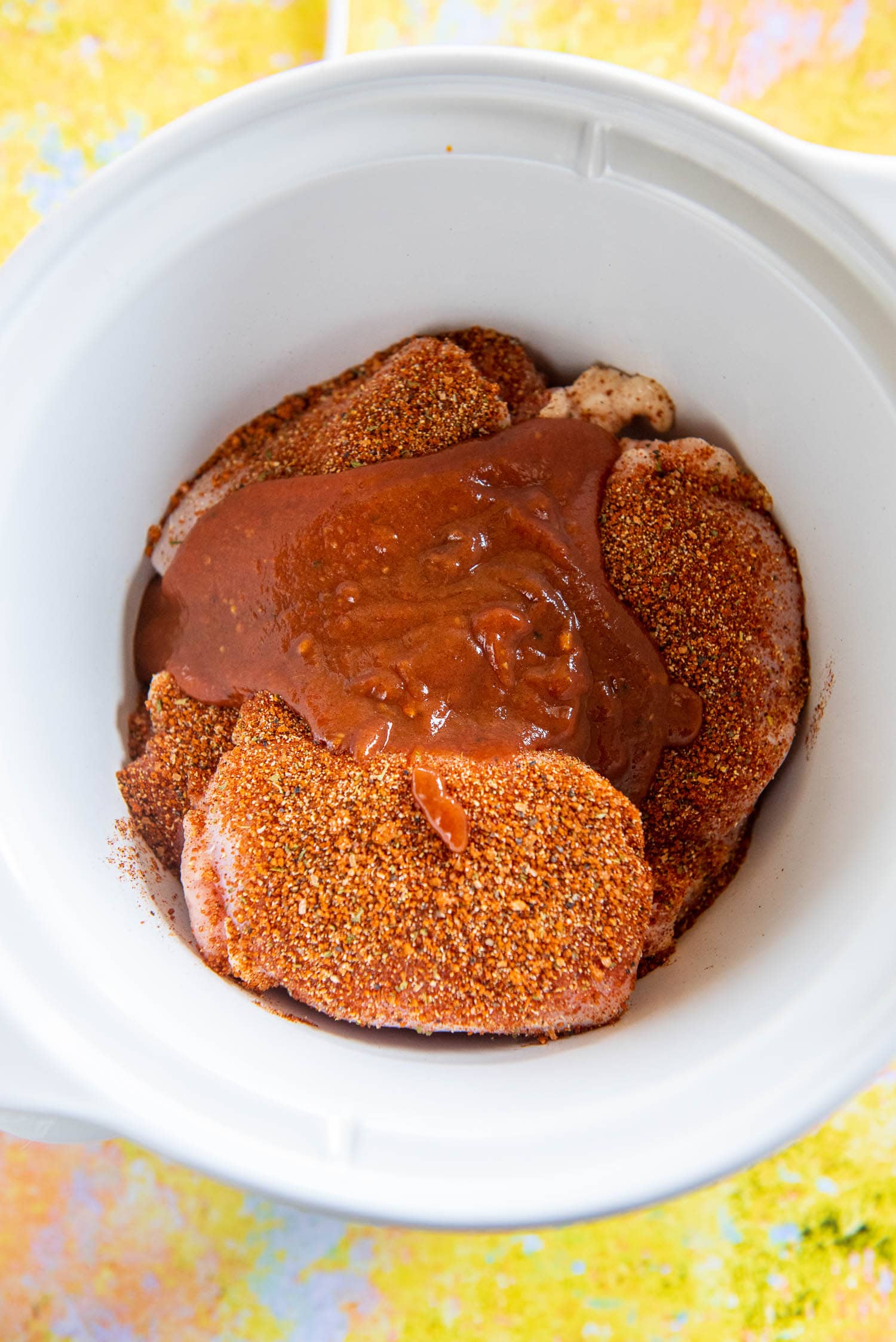 chicken with rub seasoning and bbq sauce in slow cooker