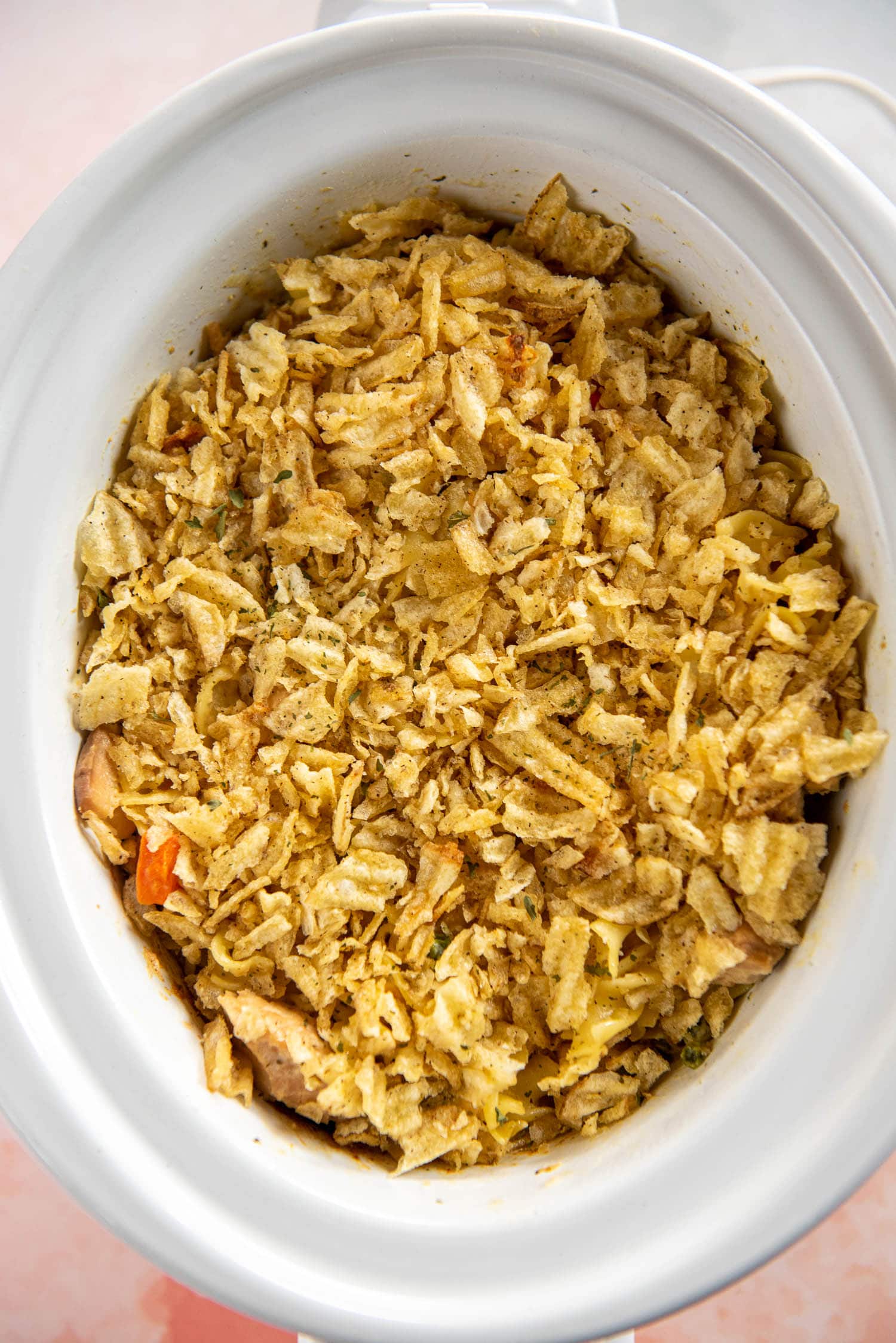oval white slow cooker with tuna noodle casserole topped with crushed chips