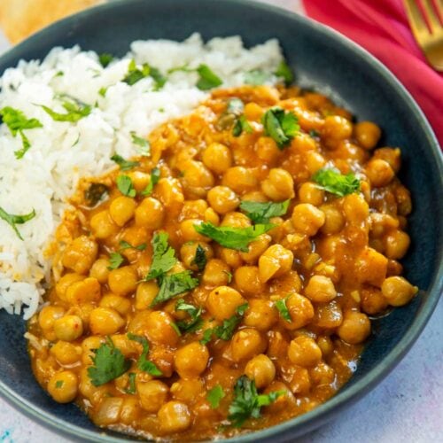 chickpeas in a curry sauce with rice on blue plate