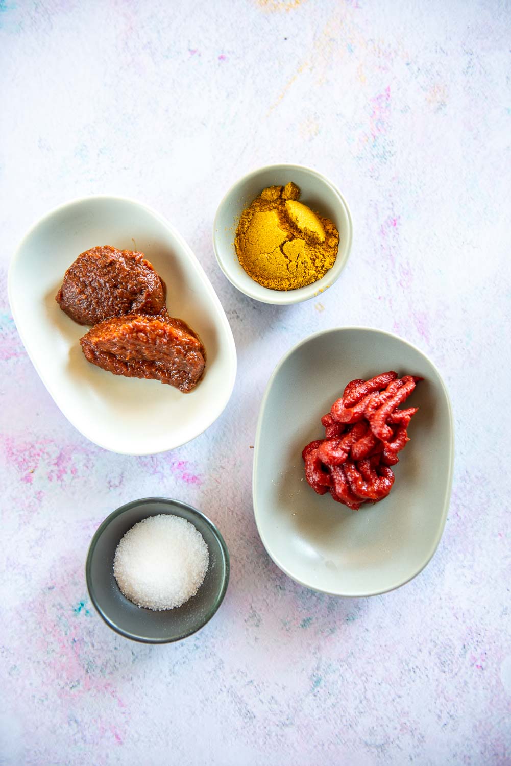 small bowls of curry paste, curry seasoning, tomato paste and salt