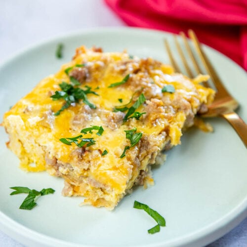 Crescent Roll Breakfast Casserole cooked square serving on a plate garnished with parsley on a blue plate with fork on plate
