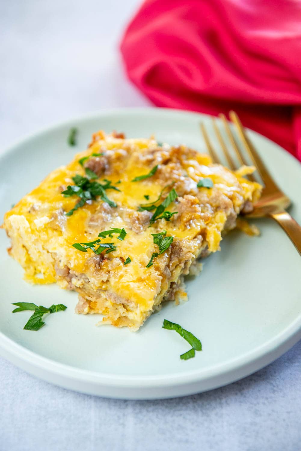 Crescent Roll Breakfast Casserole cooked square serving on a plate garnished with parsley on a blue plate with fork on plate