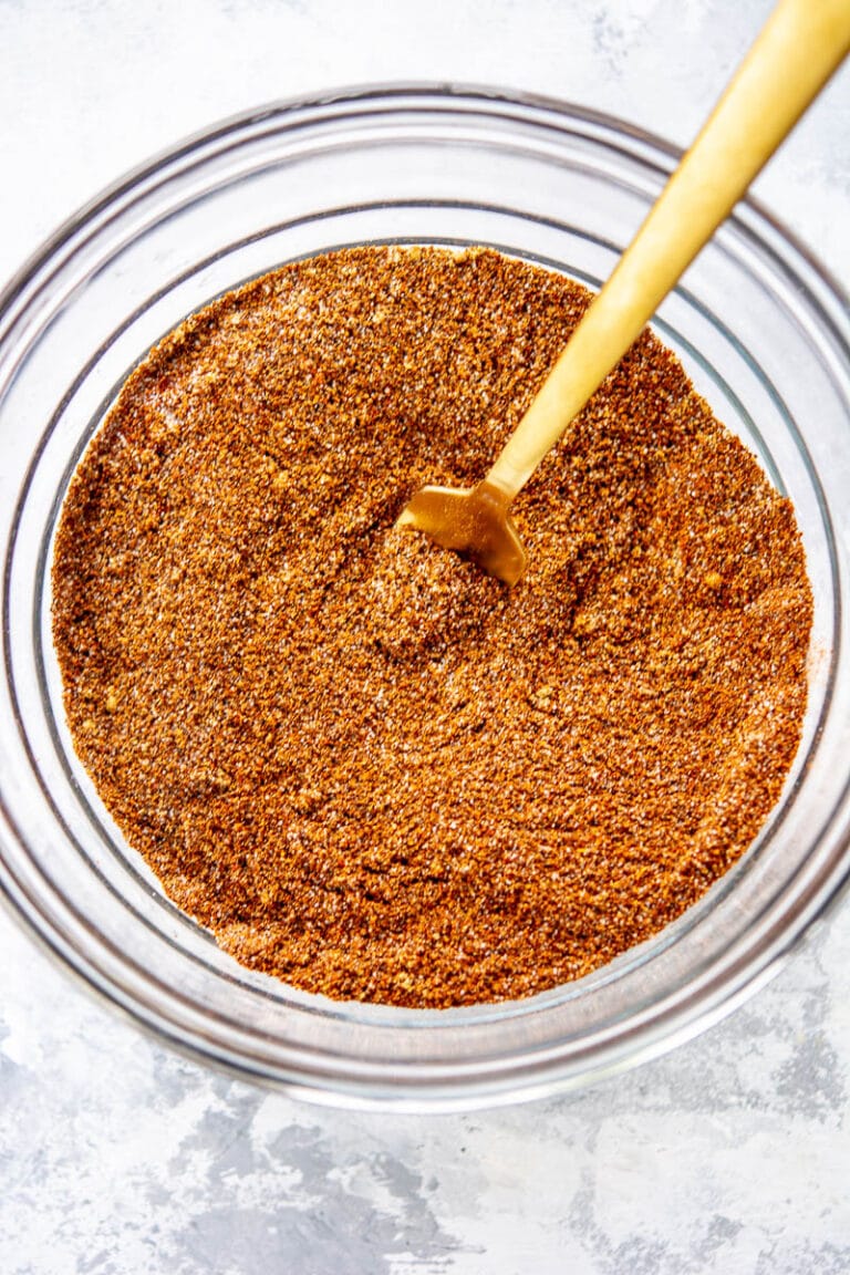 chili seasoning in a glass bowl with a wooden spoon inside