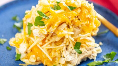 Slow Cooker Chicken Noodle Casserole served on a blue dish garnished with parsley and a golden spoon to the side