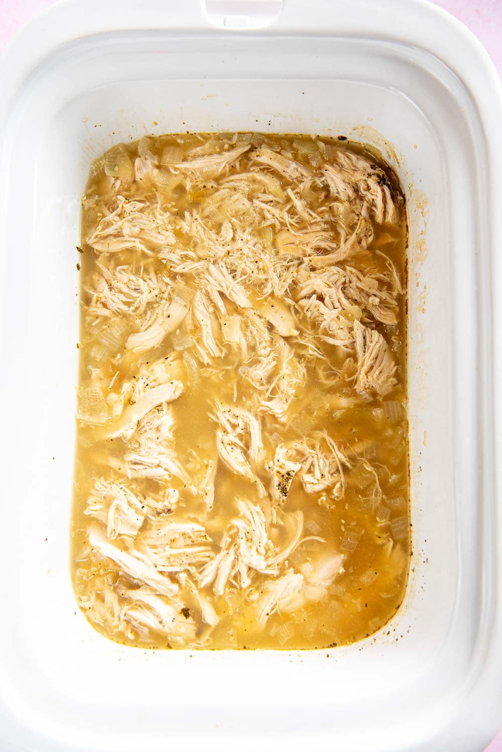 shredded chicken in a soup brown mixture in a white bowl