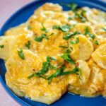 scalloped potatoes garnished served on a blue plate