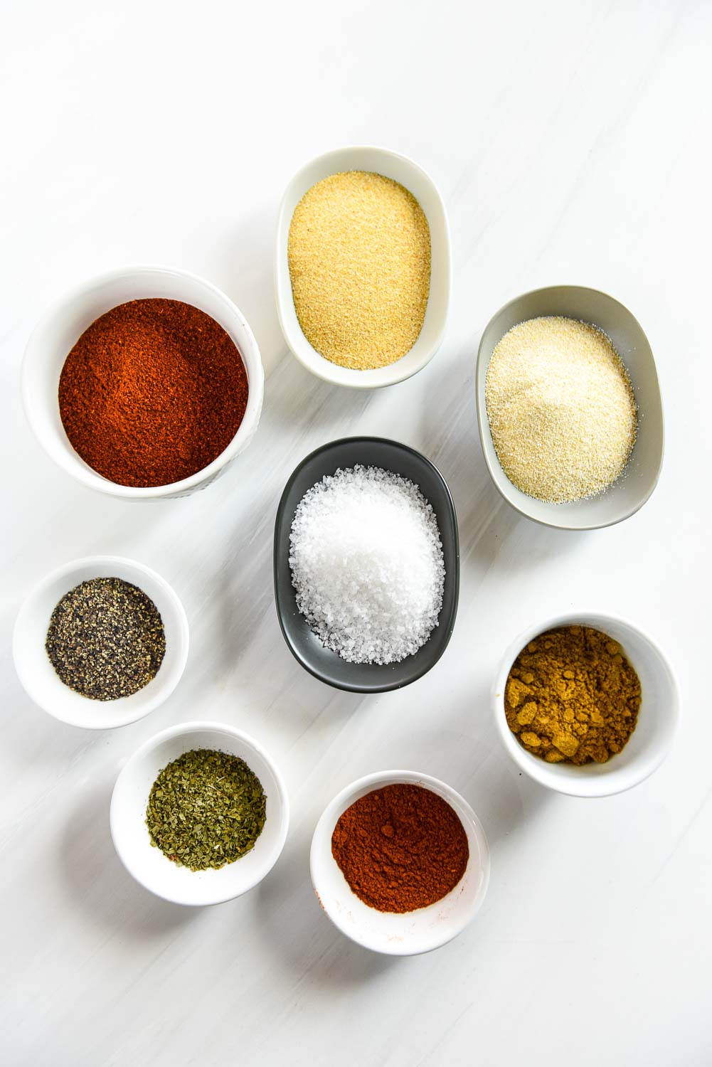 ramekins with dried spices including garlic powder, onion powder, cumin, paprika, cilantro, black pepper, salt and chili powder