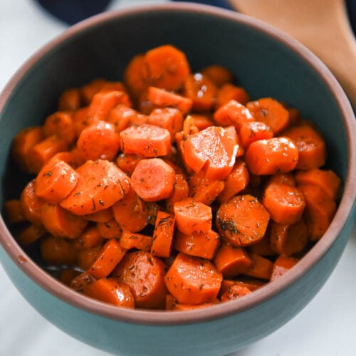 cooked pieces of carrots in a green serving bowl