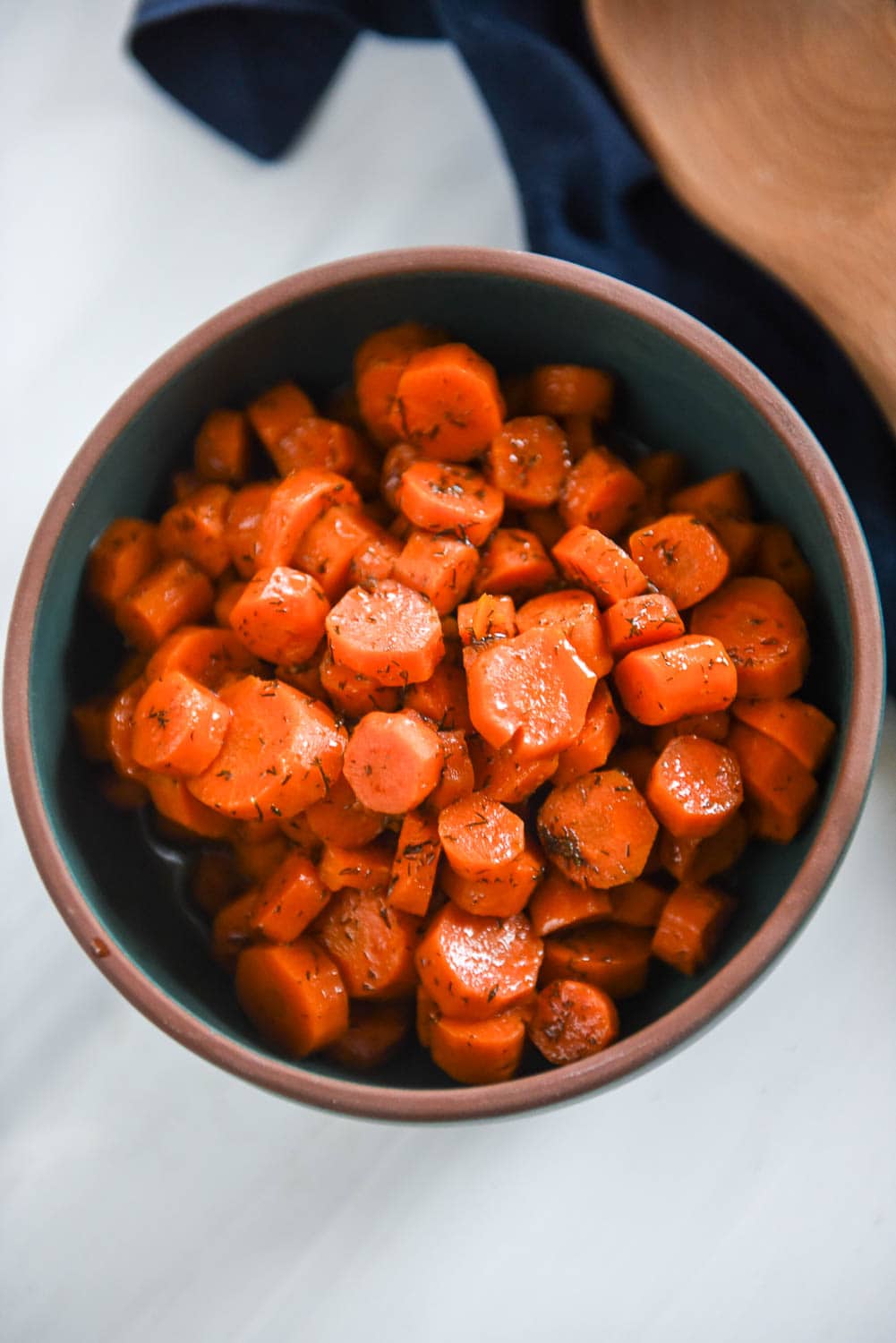 cooked carrots with herbed butter in a green bowl