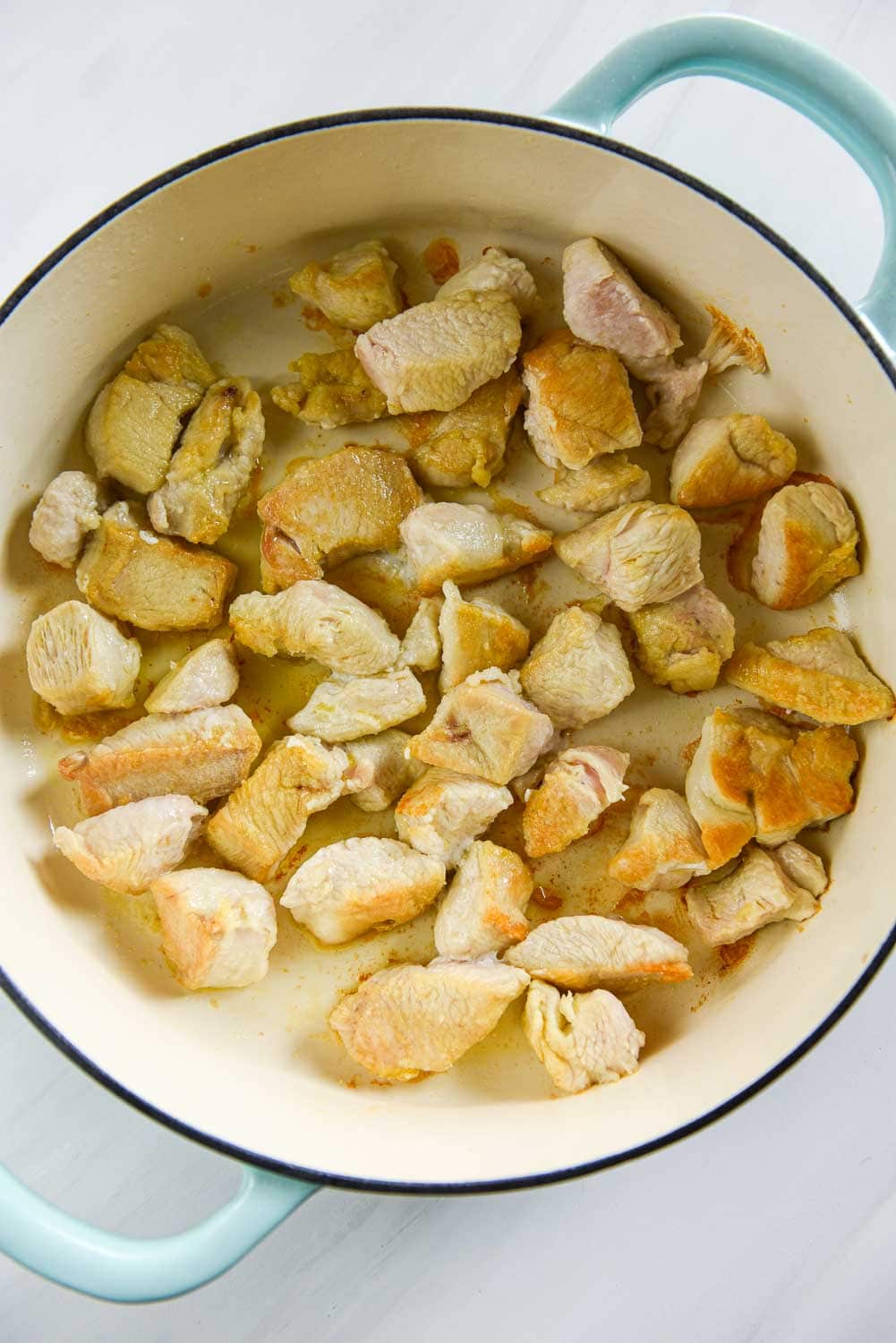 Cooked chicken pieces in shallow Dutch oven