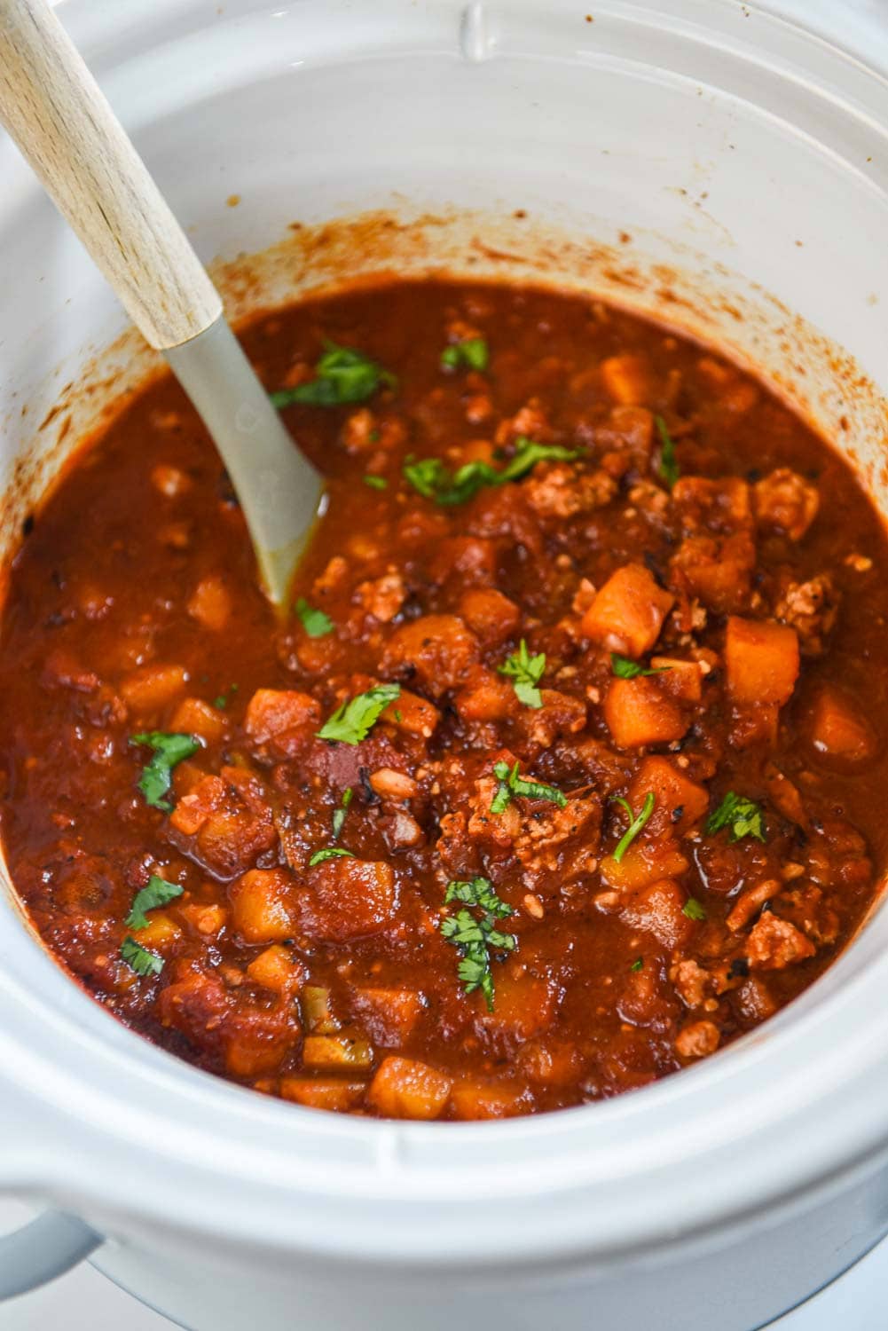 while slow cooker of turkey chili with shredded cilantro on top