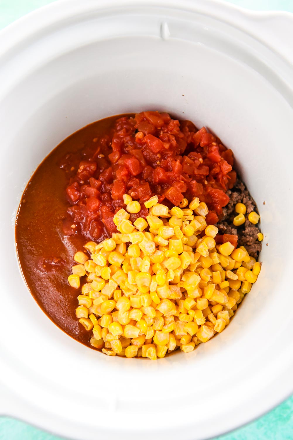 Beef, enchilada sauce, tomatoes and corn in slow cooker