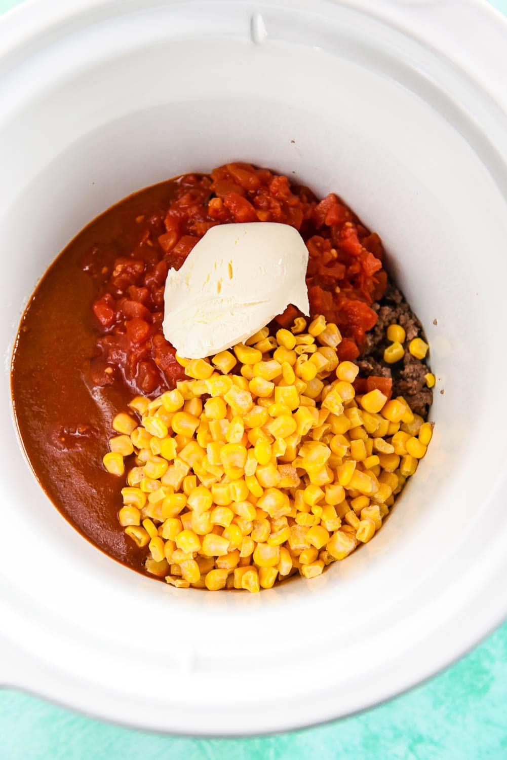 Enchilada sauce, corn, tomatoes and cream cheese in slow cooker