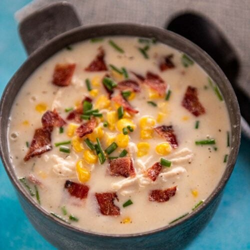 metal bowl filled with chicken corn chowder topped with chives and bacon