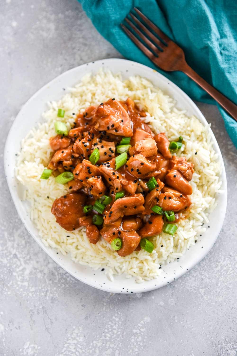 Hawaiian chicken garnished with green onions and black pepper on a bed of white rice