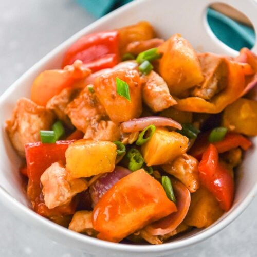 bowl filled with pineapple chicken with peppers and green onions