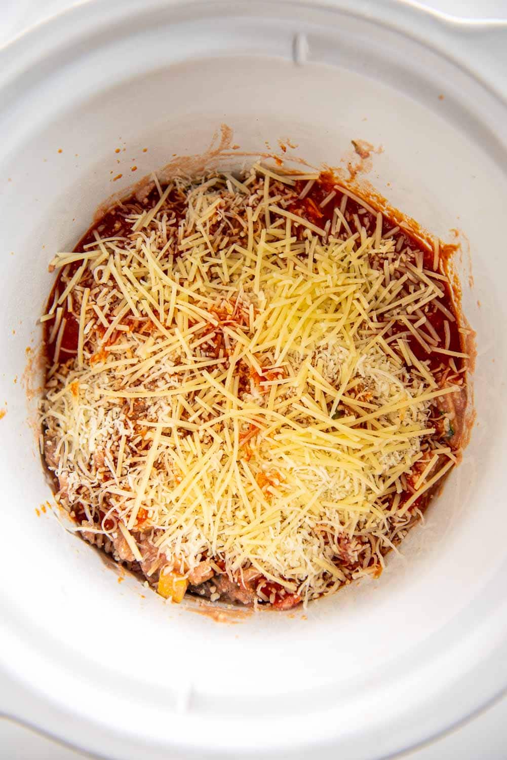 pasta bake topped with cheese ready to cook in round white slow cooker