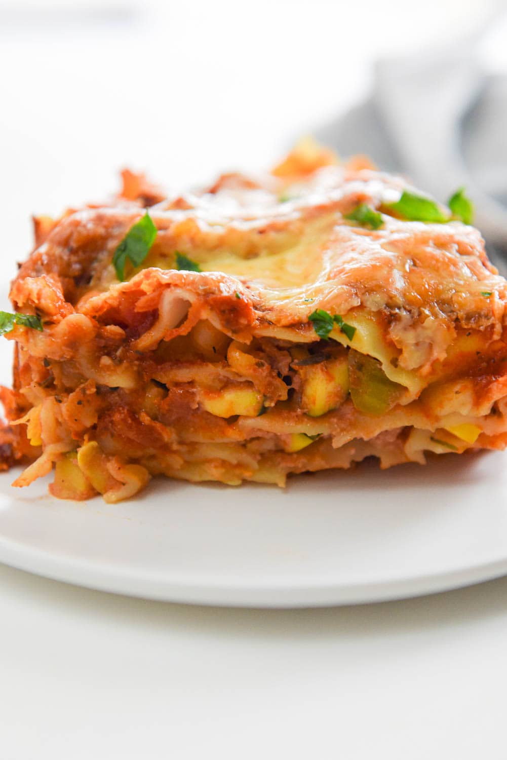 side view of veggie lasagna layers on white plate
