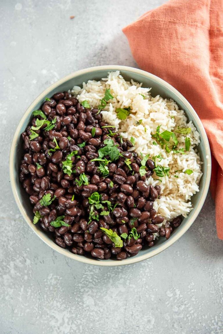 Bowl of white rice, cooked black beans, and garnished