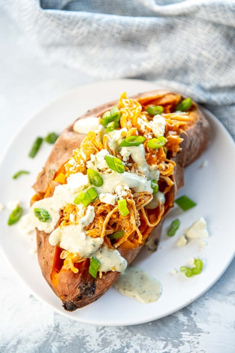 stuffed sweet potato with buffalo chicken, sauce, bacon, cheese, and green onions on top