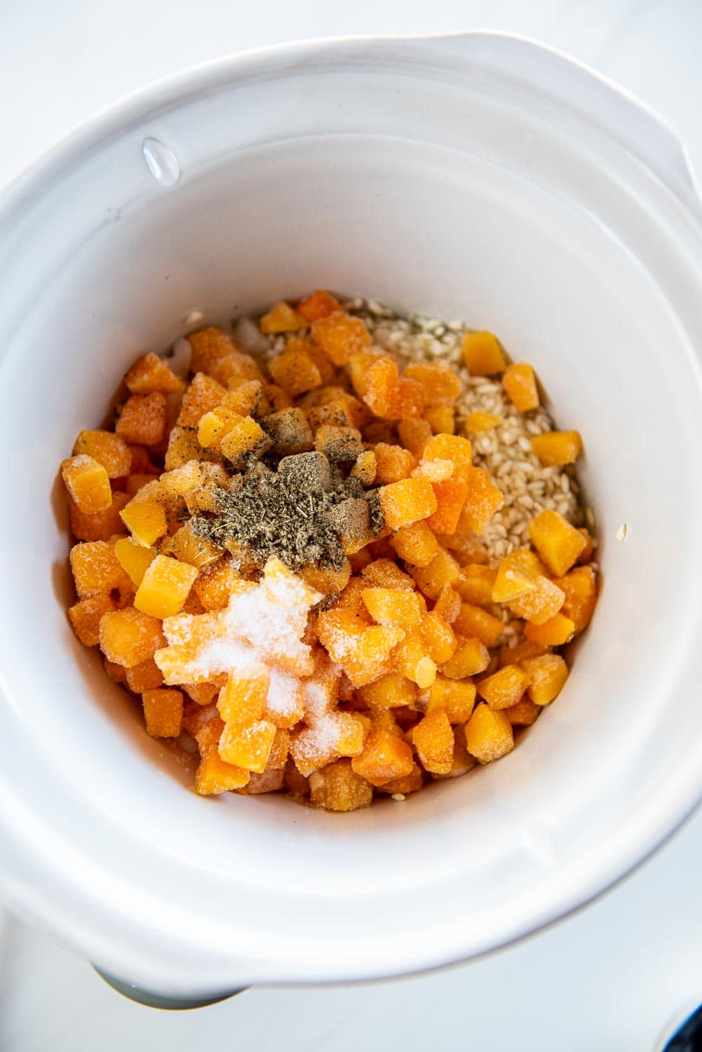 butternut squash with seasonings on top inside of slow cooker