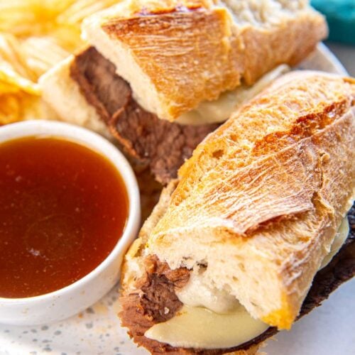 Slow Cooker French Dip Sandwich on a plate with au jus an potato chips