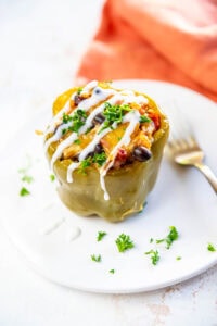 Slow Cooker Stuffed Peppers drizzled with white cream and garnished