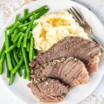 Slow Cooker Bottom Round Roast served with green beans and mashed potatoes served on plate