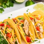 3 hard shell shredded chicken tacos on a white plate