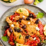 Slow Cooker Greek Chicken served on plate next to zucchini, lemon, and shallots
