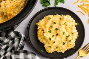 Slow Cooker Hashbrown Casserole served and garnished next to the slow slow cooker with meal inside
