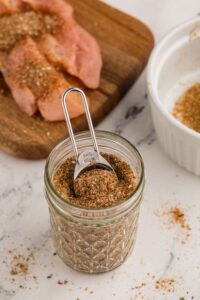 Homemade Chicken Taco Seasoning in mason jar with 5 ml tsp inside scooping the mixture