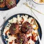 blue plate of mashed potatoes topped with three meatballs drizzled with bbq sauce